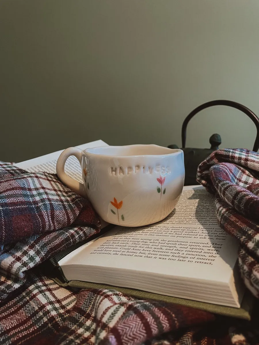 Wind-down routine to fall asleep fast: a book, a mug and a cozy blanket on the bed